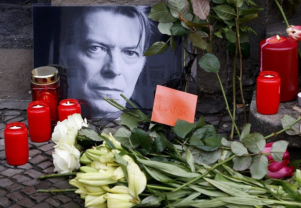 Flowers and lit candles are pictured next to a portrait of David Bowie outside the apartment house where he was living in 1976-78 in Berlin's Schoeneberg district, Germany, January 11, 2016. REUTERS/Fabrizio Bensch