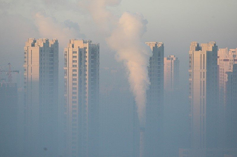 A chimney is seen in front of residential buildings during a polluted day in Harbin, Heilongjiang Province, China, January 21, 2016. REUTERS/Stringer